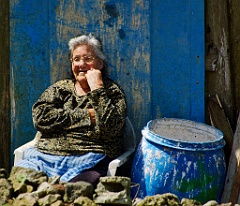 In den Bergen  Siesta - Mittagspause. Die Sonne wärmt die alte Frau, die an der Rückwand ihres kleinen Hauses sitzt.